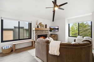 Living area featuring wood finished floors, a fireplace, healthy amount of natural light, ceiling fan, and vaulted ceiling