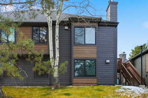 Back of property featuring stairway, a chimney, and a yard