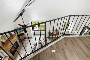 Staircase with a fireplace, wood finished floors, ceiling fan, and beam ceiling