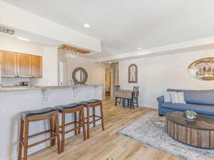 Kitchen with a breakfast bar area, light stone countertops, light wood-style flooring, and recessed lighting