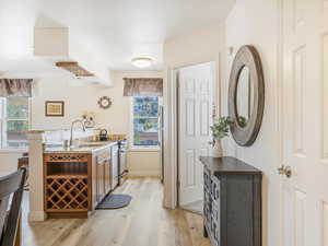 Kitchen with a peninsula, light stone counters, light wood finished floors, stainless steel electric range oven, and brown cabinetry