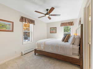 Carpeted bedroom with a baseboard heating unit and a ceiling fan