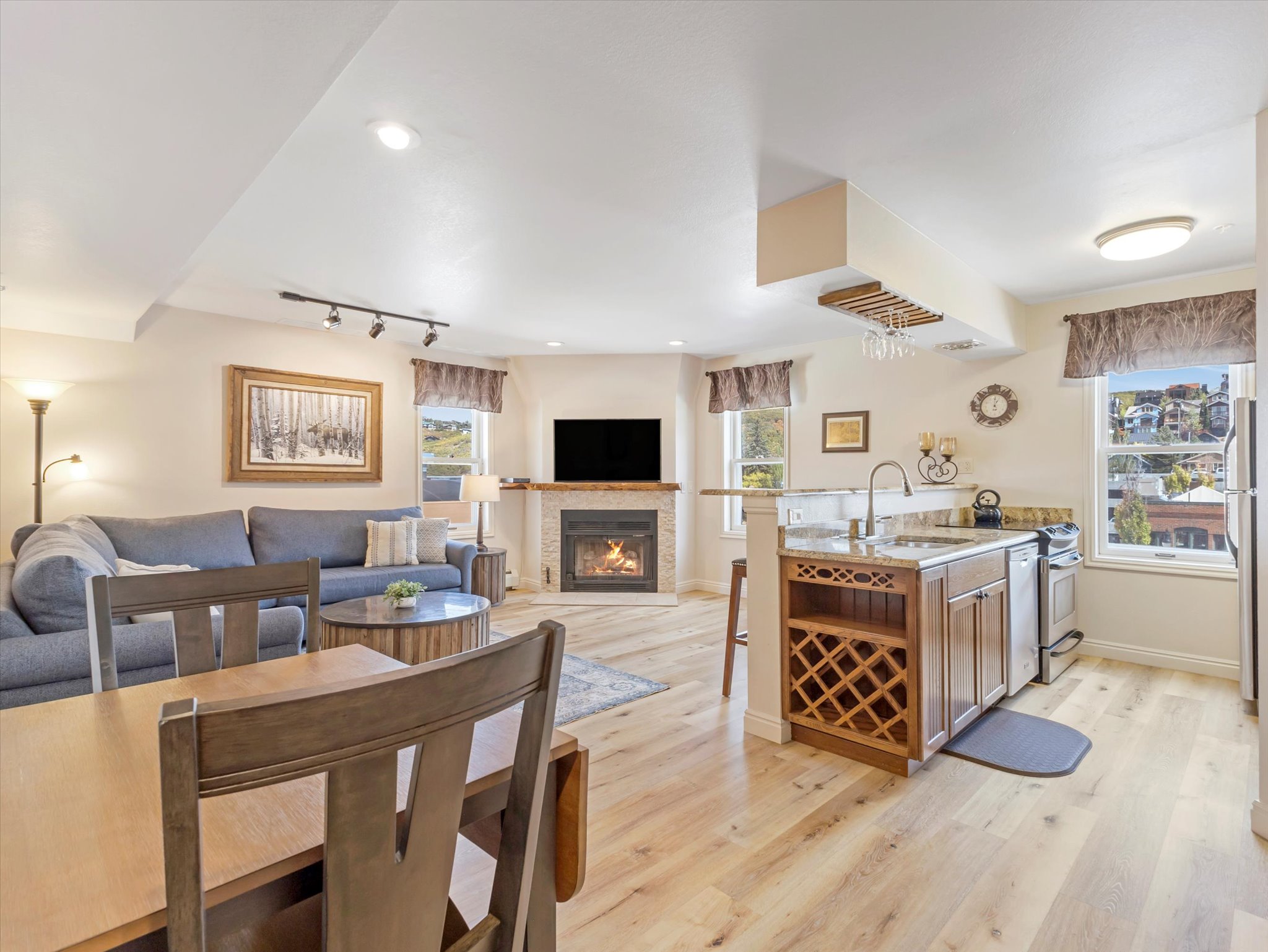 Kitchen with open floor plan, light stone counters, a peninsula, light wood-style floors, and healthy amount of natural light