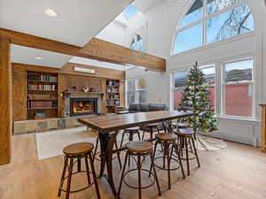 Bar area featuring a warm lit fireplace, built in shelves, light wood-type flooring, a towering ceiling, and recessed lighting