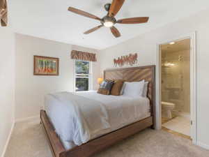 Bedroom with light carpet, ceiling fan, and connected bathroom