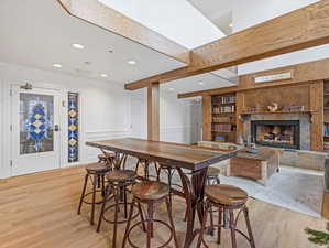 Dining room with a tiled fireplace, light wood finished floors, a decorative wall, recessed lighting, and built in features