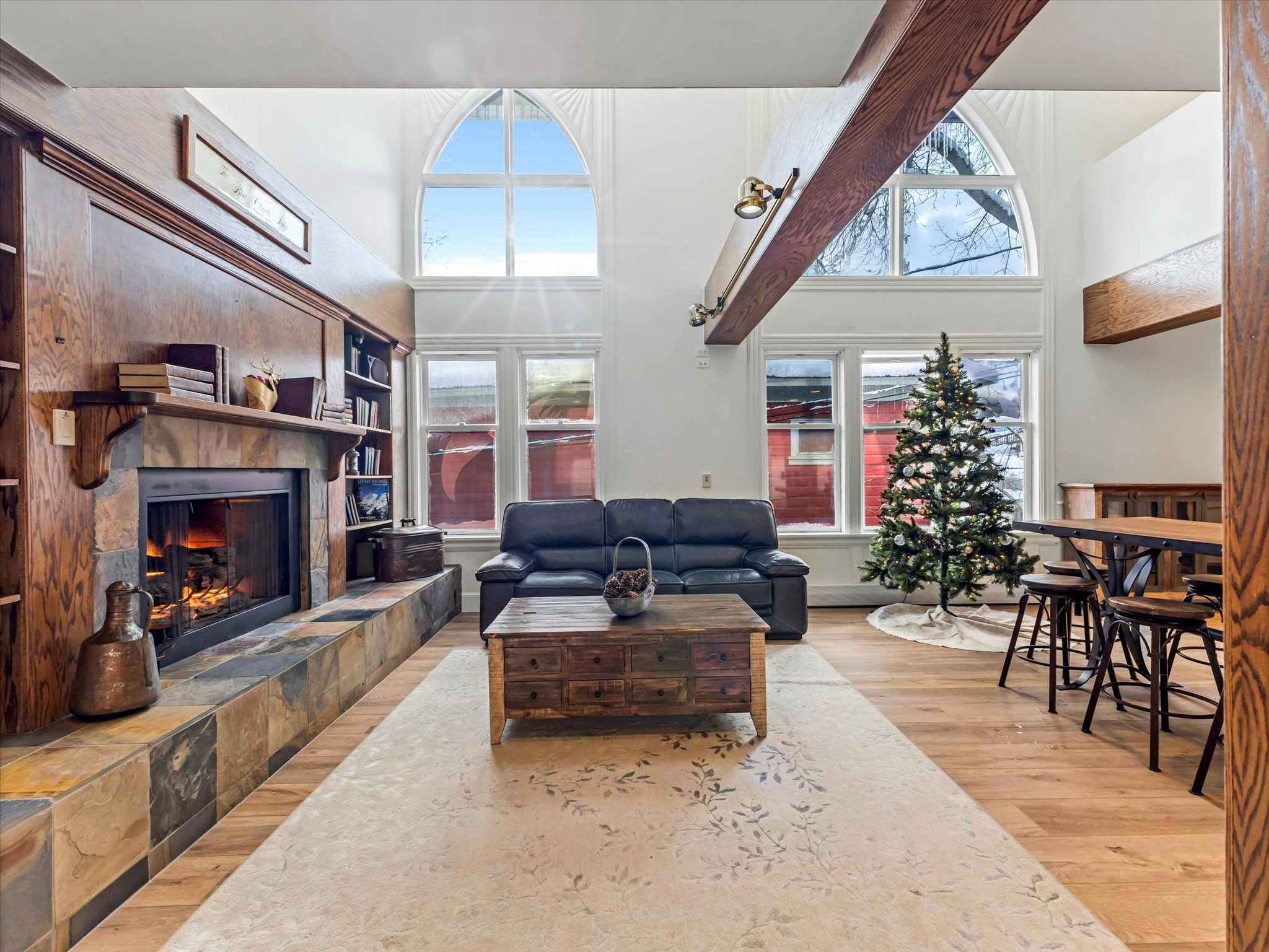 Living room featuring a towering ceiling, light wood-type flooring, a fireplace, and plenty of natural light
