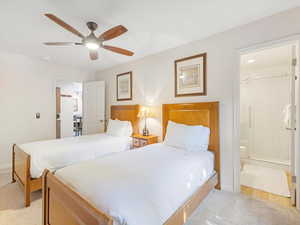 Bedroom featuring a ceiling fan, ensuite bath, and light colored carpet