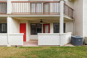 Property entrance with a ceiling fan, stucco siding, a yard, and a patio area