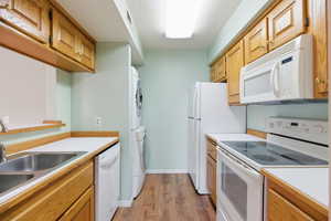 Kitchen with white appliances, light countertops, and estacked washer and dryer