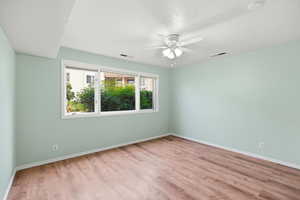 Spare room featuring light wood-style floors, a ceiling fan, and a textured ceiling