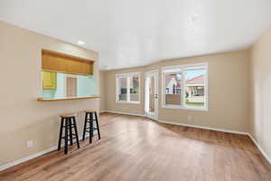 Unfurnished living room featuring light wood-style flooring and baseboards