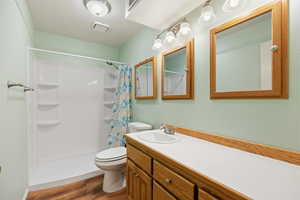 Full bath featuring a shower stall, dark wood-style flooring, vanity, and a textured ceiling