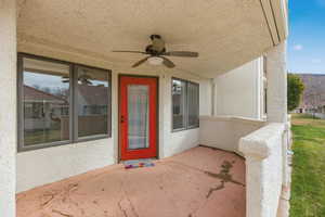 Entrance to property with a patio area, a ceiling fan, and stucco siding