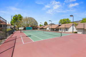 View of tennis court with a residential view and community basketball court