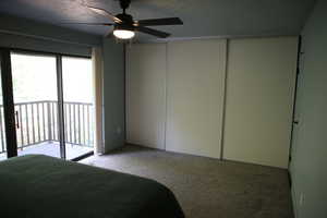 Carpeted bedroom featuring access to outside, ceiling fan, and a textured ceiling