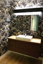Bathroom featuring wallpapered walls, vanity, and wood finished floors