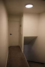Hallway featuring dark carpet and baseboards
