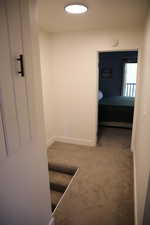 Hall featuring light carpet and baseboards