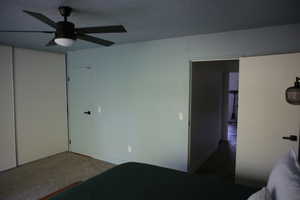 Unfurnished bedroom with ceiling fan, a closet, dark colored carpet, and a textured ceiling