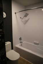 Bathroom featuring shower / bath combination with curtain and dark wood finished floors