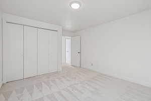 Unfurnished bedroom with light carpet and a closet