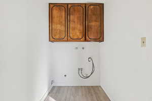 Laundry area featuring cabinet space, hookup for a washing machine, light wood-style floors, and hookup for a gas dryer