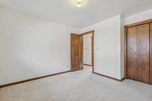 Unfurnished bedroom with a closet, a textured ceiling, and light carpet