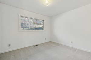 Empty room with light carpet and a textured ceiling