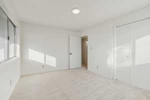 Unfurnished bedroom with light carpet and baseboards
