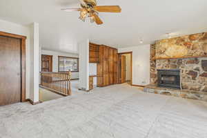 Unfurnished living room with a fireplace, carpet flooring, and ceiling fan