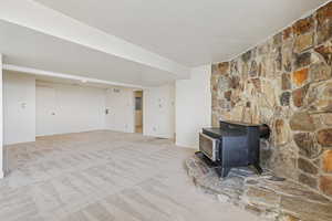 Unfurnished living room featuring a wood stove and carpet flooring