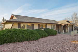 View of front of house with a garage, a shingled roof, brick siding, and covered porch