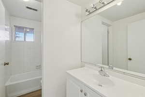 Full bathroom with vanity, bathing tub / shower combination, and dark wood finished floors