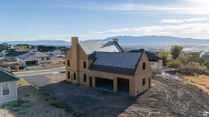 View of side of home featuring a chimney, a mountain view, dirt driveway, a patio, and a residential view