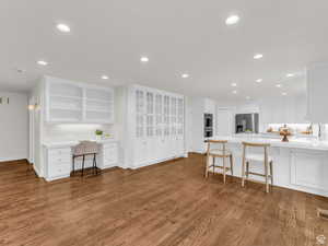 Kitchen with a peninsula, a breakfast bar area, white cabinetry, dark wood-type flooring, and open shelves
