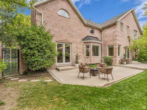 Rear view of house with brick siding, a patio area, an outdoor hangout area, and a lawn