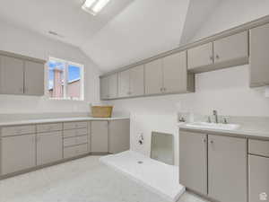 Laundry area with vaulted ceiling, hookup for a washing machine, cabinet space, light floors, and gas dryer hookup