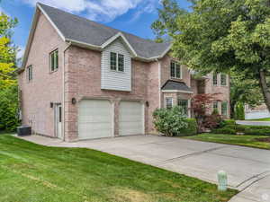 Traditional-style home with brick siding, a front lawn, driveway, an attached garage, and roof with shingles
