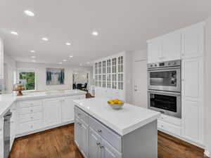 Kitchen with white cabinetry, stainless steel double oven, a kitchen island, recessed lighting, and dark wood-type flooring