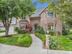 Traditional home with a front lawn, brick siding, a shingled roof, a garage, and concrete driveway