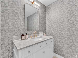 Bathroom featuring wallpapered walls and vanity