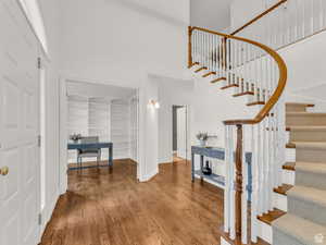 Foyer entrance with a towering ceiling, wood finished floors, and stairs