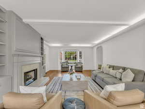 Living room with arched walkways, a premium fireplace, and wood finished floors