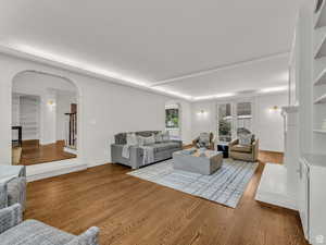 Living area with arched walkways, wood finished floors, and stairway