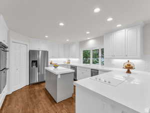 Kitchen with a kitchen island, white cabinets, appliances with stainless steel finishes, light wood-style flooring, and recessed lighting