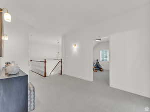 Unfurnished room featuring an upstairs landing and carpet flooring