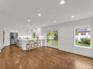 Kitchen with recessed lighting, a peninsula, white cabinetry, a kitchen breakfast bar, and stainless steel fridge with ice dispenser