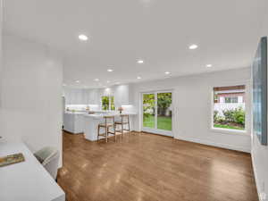 Kitchen with a kitchen bar, white cabinets, recessed lighting, dark wood finished floors, and healthy amount of natural light