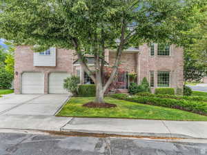 View of front facade featuring a front lawn, brick siding, driveway, and a garage